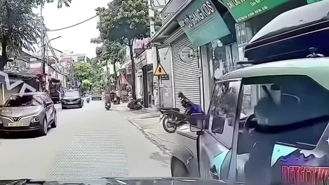 Đường phố hẹp có ô tô đỗ sát lề, khung hình camera hành trình trước lúc cửa xe bật ra